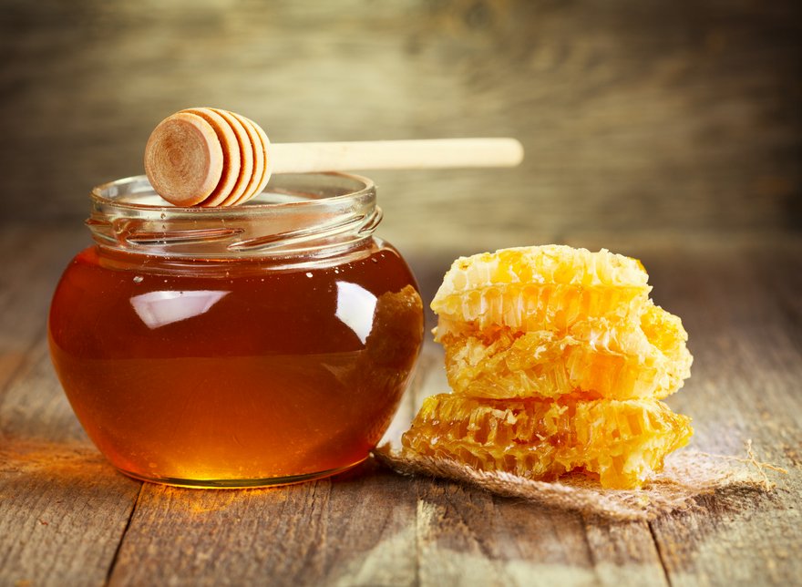 jar of honey with honeycomb on wooden table